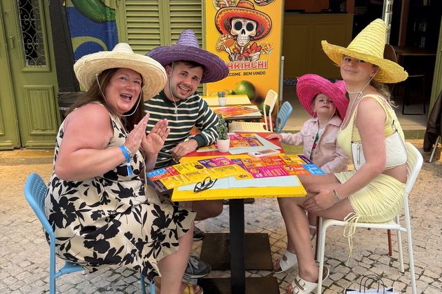 A family at a street table at Mariachi with the skull menu board and the restaurant sign behind them