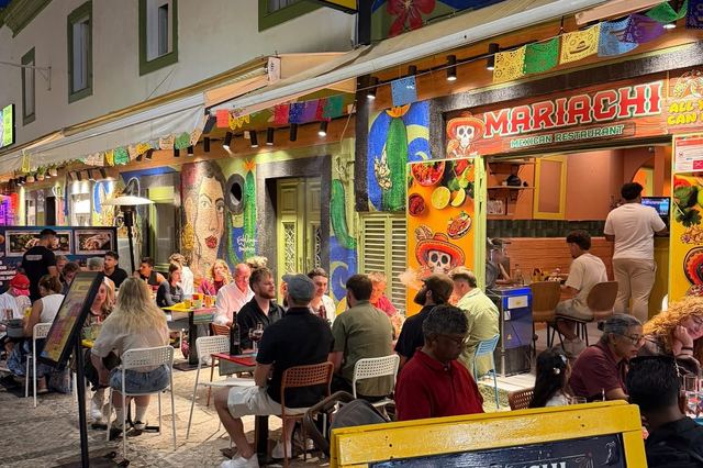 Mariachi's tables on the cobbled Old Town street at night under the lit sign and bunting